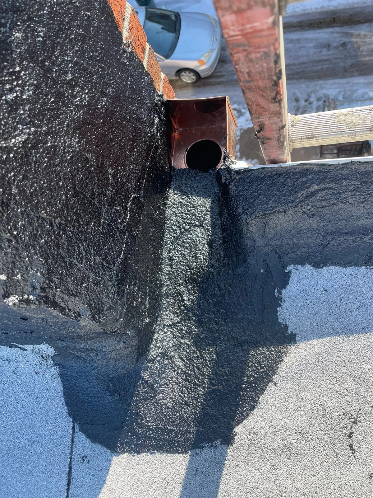 Water sitting at an old drain box on a flat roof before the crew replaced it