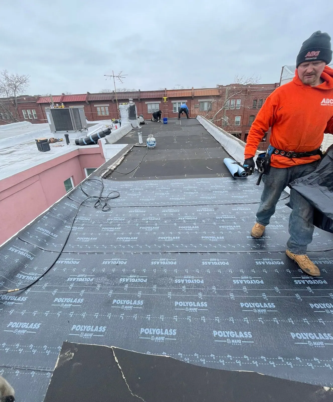 A Made in America Roofing crew member rolling out new roofing on a Philadelphia rowhome roof
