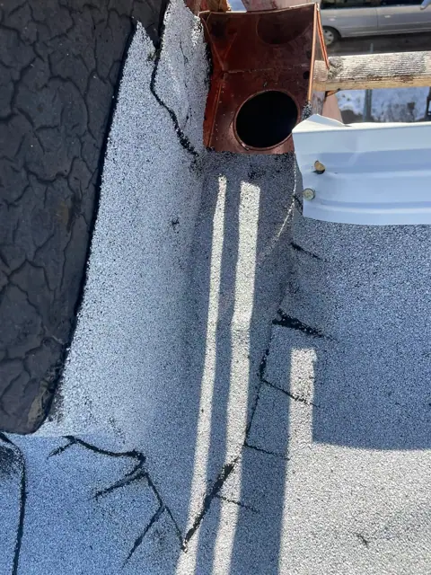 The copper drain box sealed into the new white granulated roof